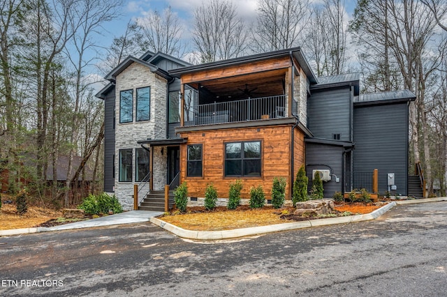 contemporary home with a balcony, a ceiling fan, stone siding, and crawl space