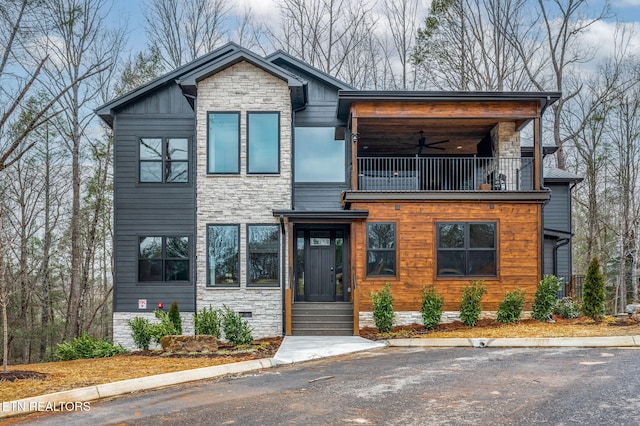 contemporary home with stone siding, a balcony, and ceiling fan