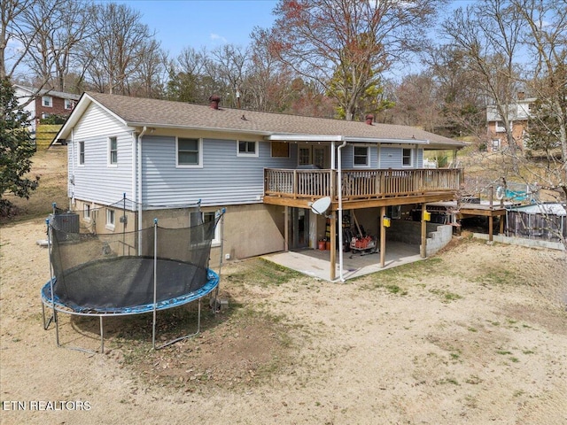 rear view of property with a patio, central air condition unit, a trampoline, and a wooden deck