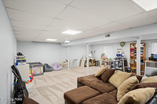 living area featuring a drop ceiling and carpet floors