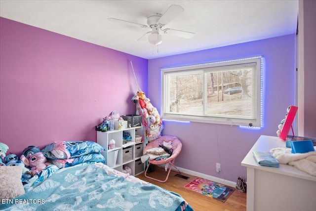 bedroom featuring a ceiling fan, visible vents, wood finished floors, and baseboards