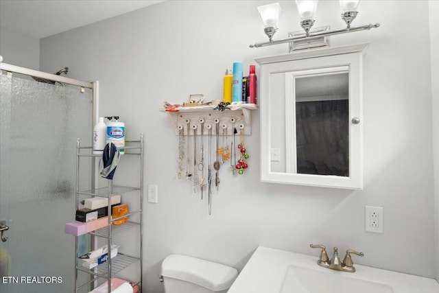 bathroom with a stall shower, toilet, and a sink