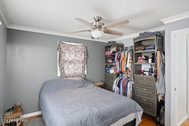 bedroom featuring baseboards, crown molding, a ceiling fan, and wood finished floors