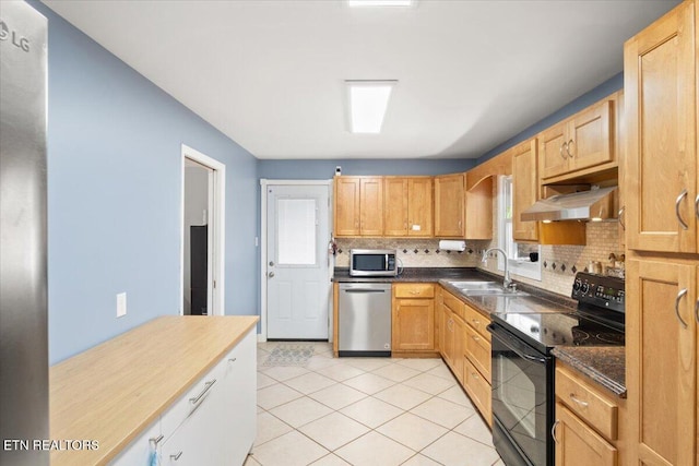 kitchen with under cabinet range hood, decorative backsplash, light tile patterned flooring, stainless steel appliances, and a sink