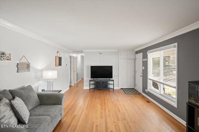 living area featuring visible vents, baseboards, light wood finished floors, and ornamental molding