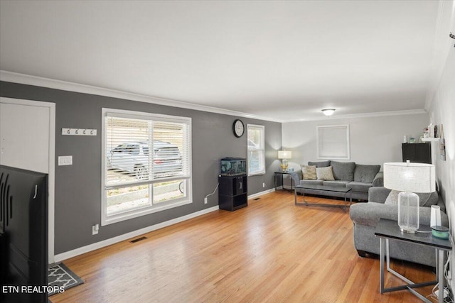 living room featuring a wealth of natural light, light wood-type flooring, and ornamental molding