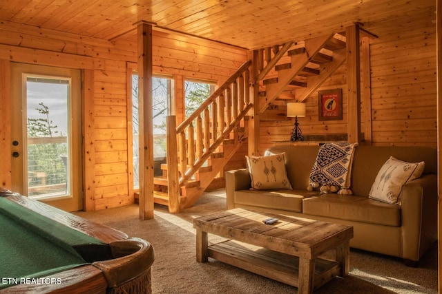 carpeted living room with plenty of natural light, wood ceiling, wooden walls, and stairs