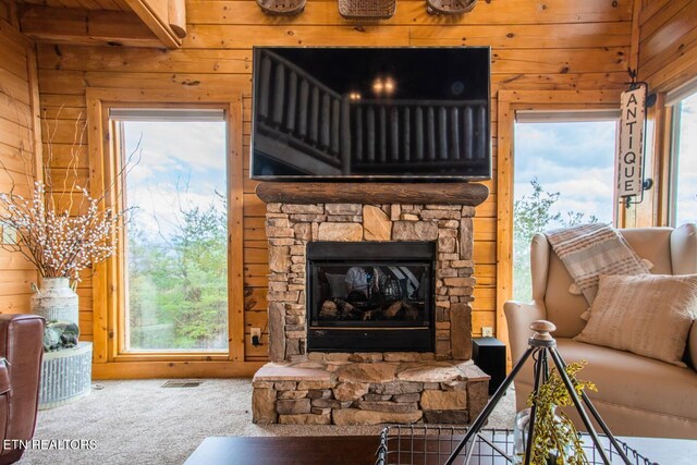 carpeted living area with visible vents, a fireplace, and wooden walls