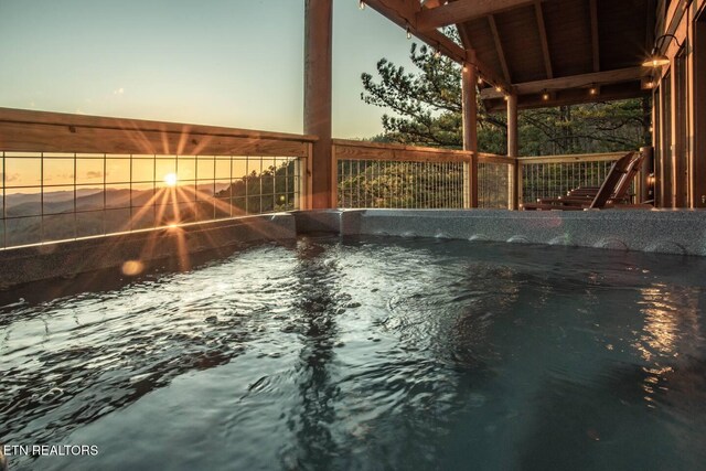 view of pool with fence and a hot tub