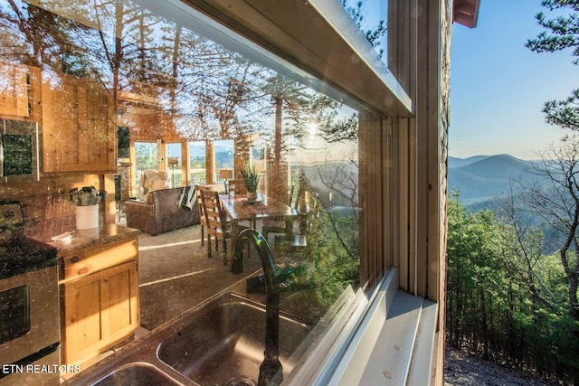 exterior space featuring dark countertops, stainless steel microwave, a sink, a mountain view, and range