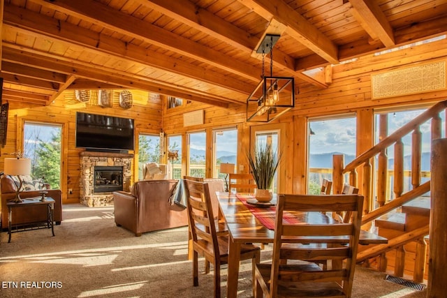 dining space featuring carpet floors, wood walls, wooden ceiling, and beamed ceiling