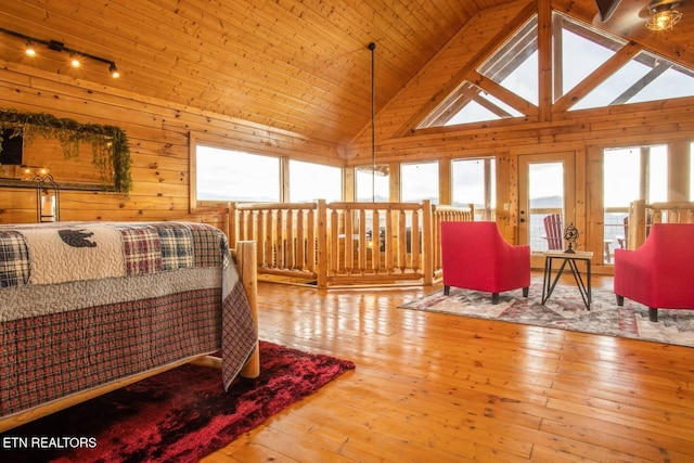 bedroom featuring high vaulted ceiling, multiple windows, wood walls, and hardwood / wood-style floors