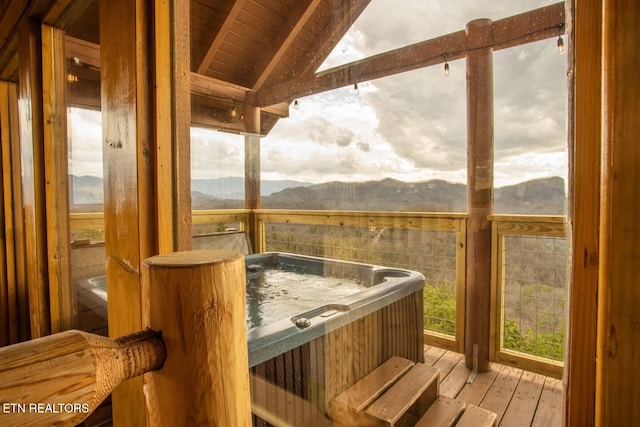 interior space with lofted ceiling with beams, wooden ceiling, a mountain view, and a jacuzzi