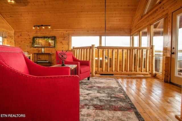 living area with lofted ceiling, wood-type flooring, rail lighting, wood walls, and wooden ceiling