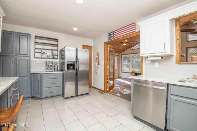 kitchen featuring tasteful backsplash, visible vents, gray cabinetry, stainless steel appliances, and open shelves