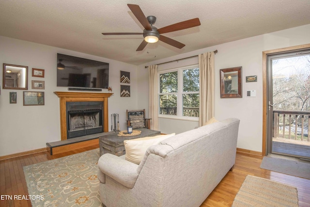 living area featuring a fireplace with raised hearth, a healthy amount of sunlight, and light wood-type flooring