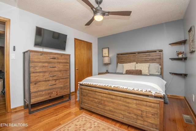 bedroom featuring light wood-style flooring, visible vents, and a textured ceiling