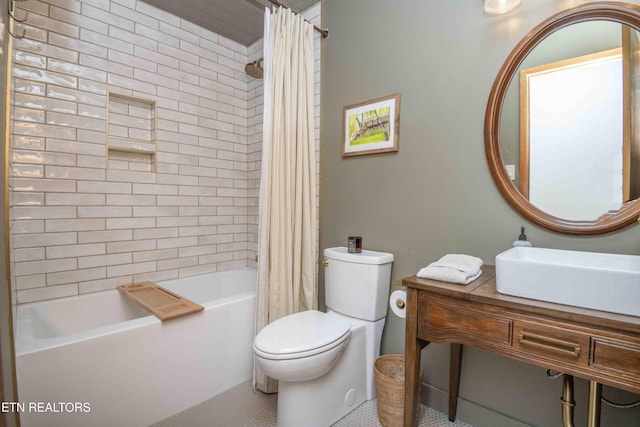 bathroom featuring a sink, shower / bath combo with shower curtain, and toilet