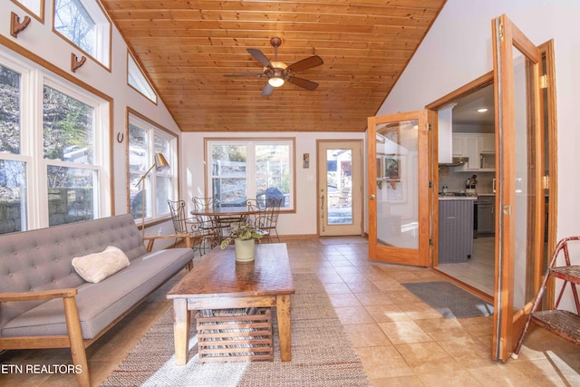 interior space featuring baseboards, ceiling fan, wood ceiling, light tile patterned flooring, and high vaulted ceiling