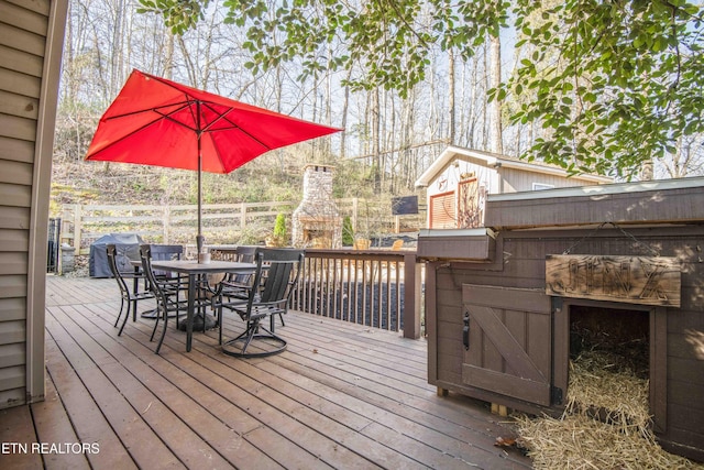 wooden terrace featuring area for grilling, outdoor dining area, and a fireplace