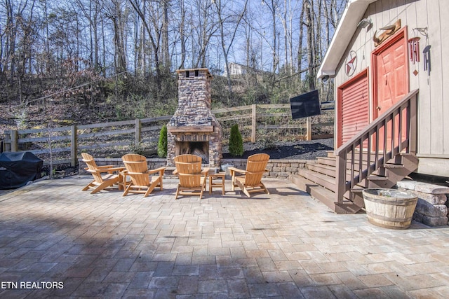 view of patio / terrace featuring entry steps, an outdoor stone fireplace, a grill, and fence