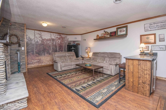 living room featuring a textured ceiling, crown molding, baseboards, and wood finished floors