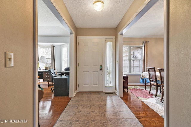 entrance foyer with a textured ceiling, baseboards, and wood finished floors