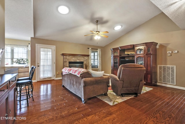 living room featuring visible vents, plenty of natural light, a brick fireplace, and vaulted ceiling