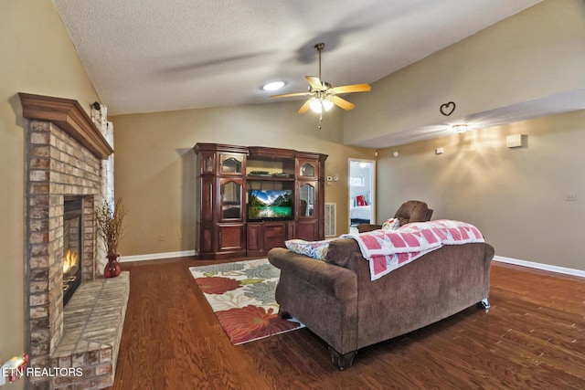 living area featuring lofted ceiling, a fireplace, dark wood-type flooring, and a textured ceiling