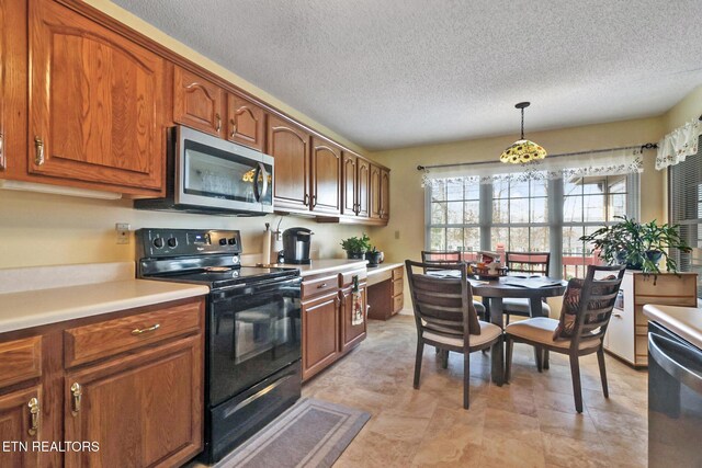 kitchen with pendant lighting, light countertops, appliances with stainless steel finishes, brown cabinetry, and a textured ceiling