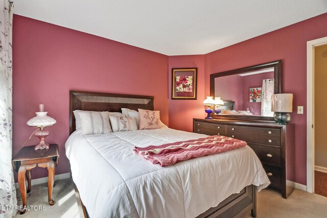 bedroom with light colored carpet and baseboards