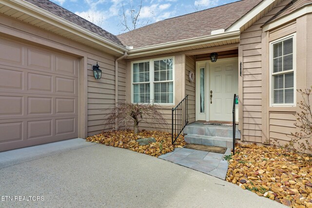 property entrance featuring a garage and a shingled roof