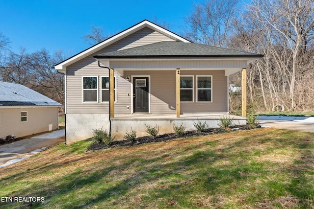 bungalow featuring a porch, a front yard, and a shingled roof