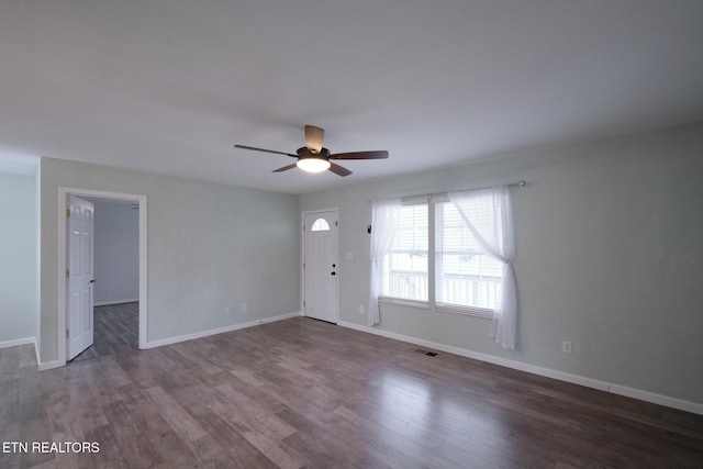 interior space featuring a ceiling fan, visible vents, baseboards, and wood finished floors