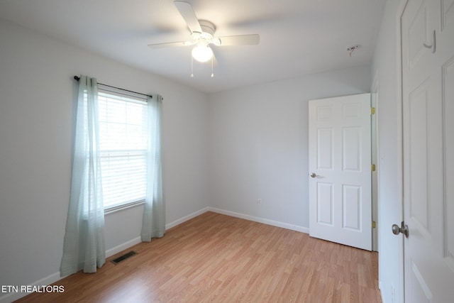 empty room featuring light wood finished floors, baseboards, visible vents, and a ceiling fan