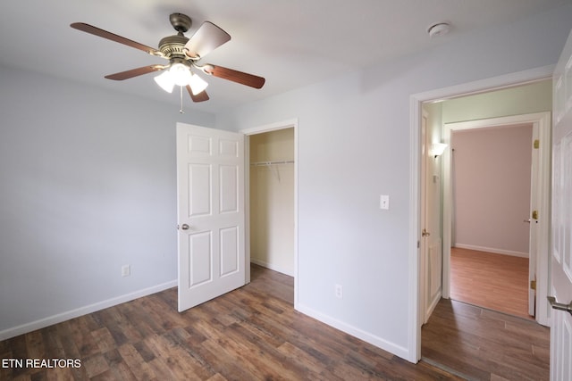 unfurnished bedroom featuring a closet, dark wood finished floors, baseboards, and ceiling fan