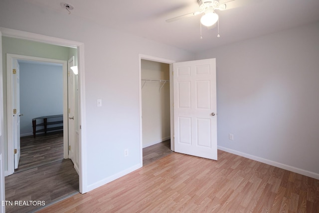 unfurnished bedroom with a closet, light wood-type flooring, a ceiling fan, and baseboards