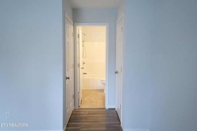 corridor with dark wood-style floors and baseboards