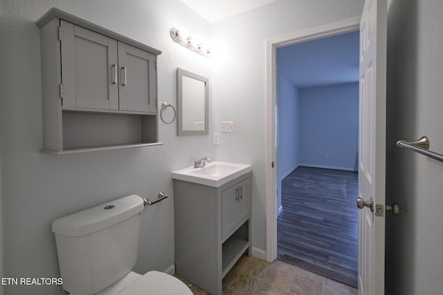 half bathroom with tile patterned floors, vanity, toilet, and baseboards