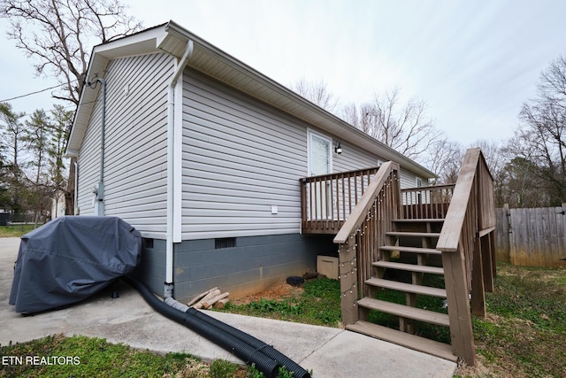 view of side of home featuring a deck, crawl space, fence, and stairway