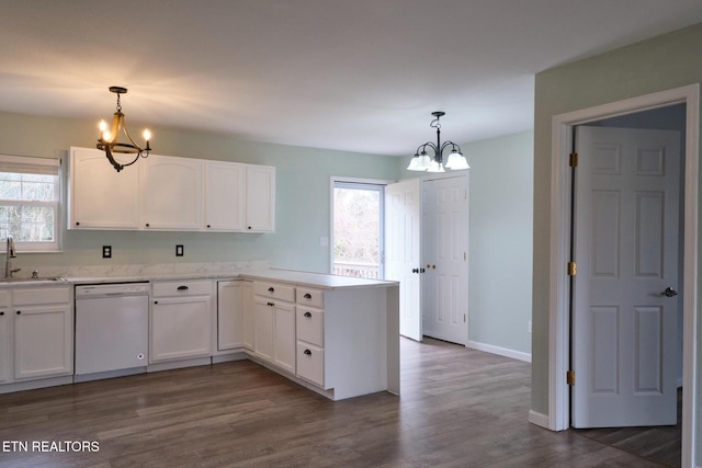 kitchen with a peninsula, white dishwasher, a sink, and an inviting chandelier