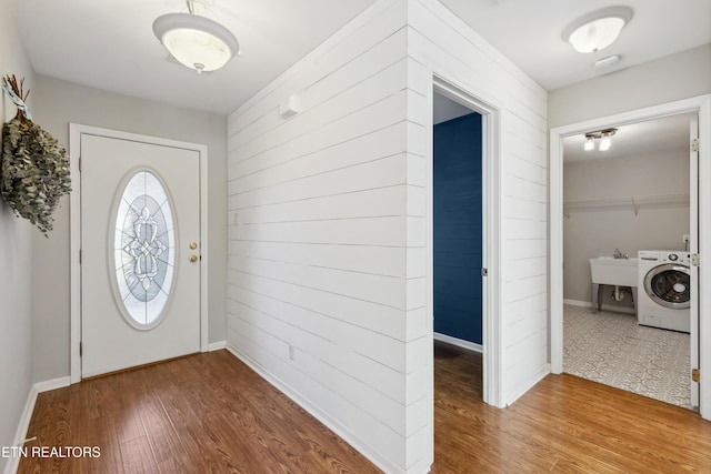 foyer entrance featuring washer / clothes dryer, wood finished floors, and baseboards