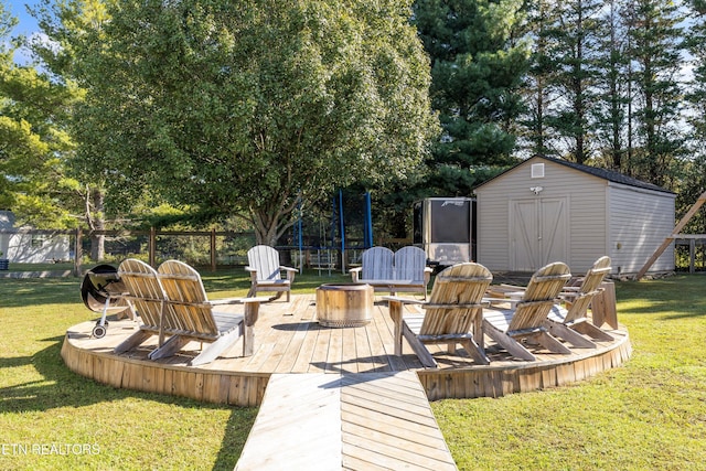 wooden terrace featuring a shed, an outdoor fire pit, a yard, and an outdoor structure