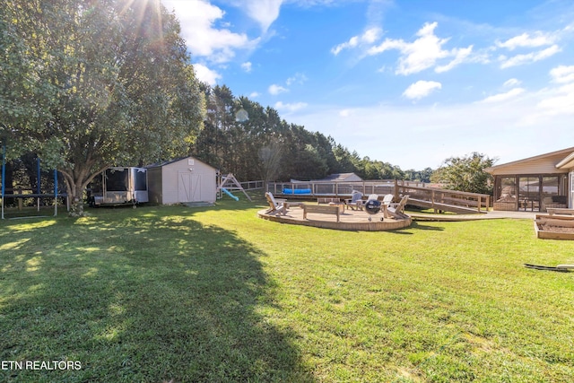 view of yard featuring an outbuilding, a storage unit, fence, and a wooden deck