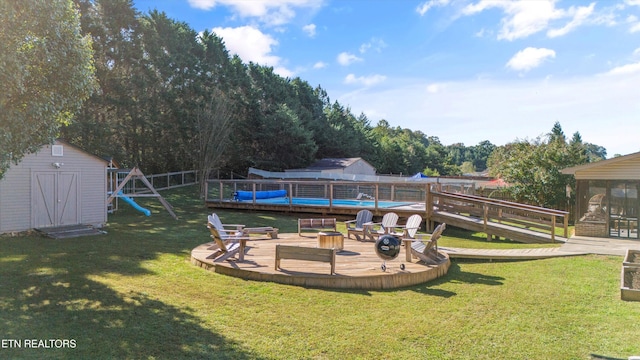 view of yard with an outbuilding, a playground, a storage unit, and a wooden deck