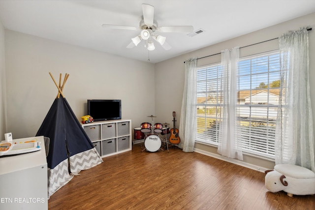 rec room with wood finished floors, visible vents, and ceiling fan