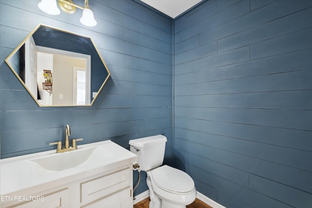 half bathroom featuring toilet, vanity, and wood finished floors