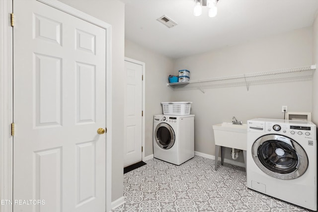 clothes washing area featuring visible vents, washer and clothes dryer, a sink, baseboards, and laundry area