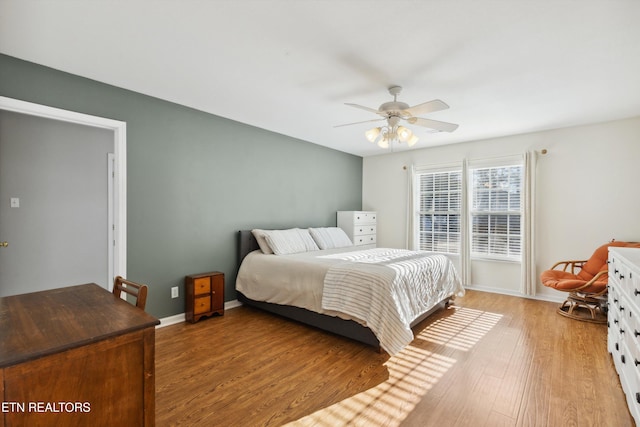 bedroom featuring baseboards, light wood-style floors, and a ceiling fan