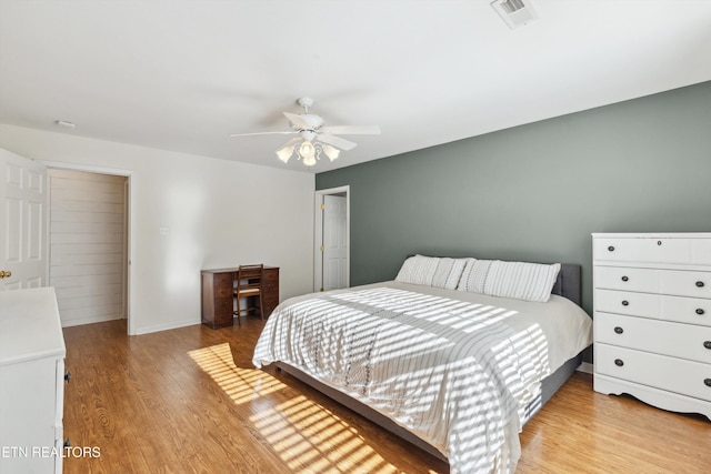 bedroom with ceiling fan, light wood-style floors, visible vents, and baseboards